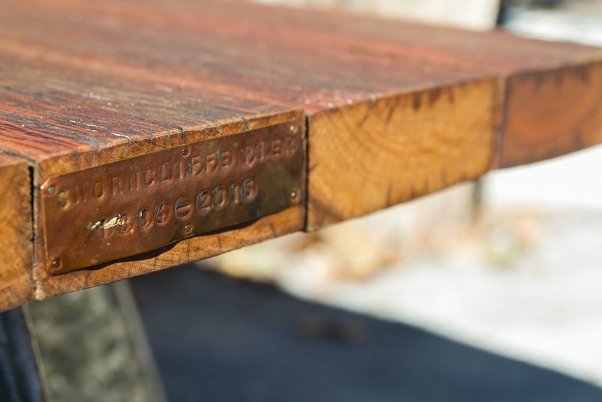 A plaque is applied to each wooden bench made from the pier.
