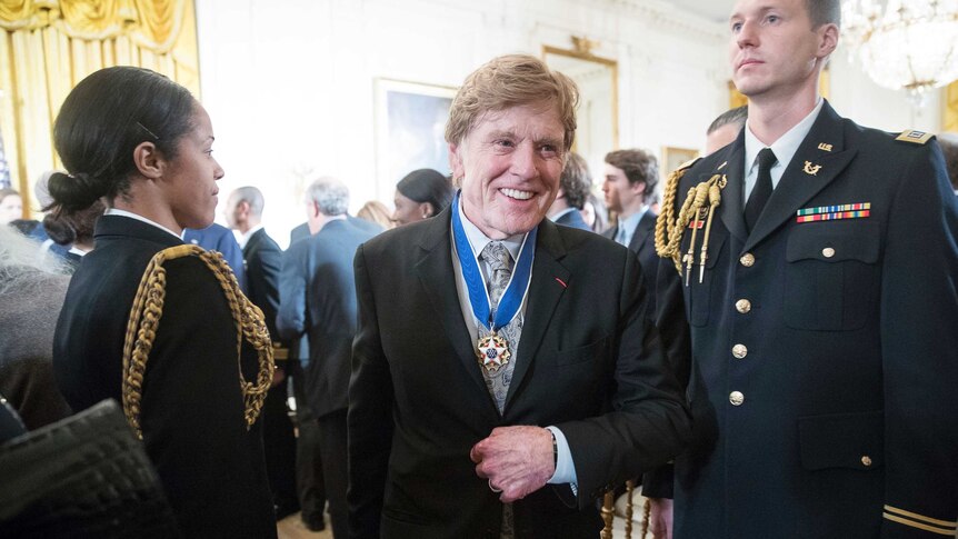Robert Redford departs the ceremony with the medal of freedom hanging around his neck.
