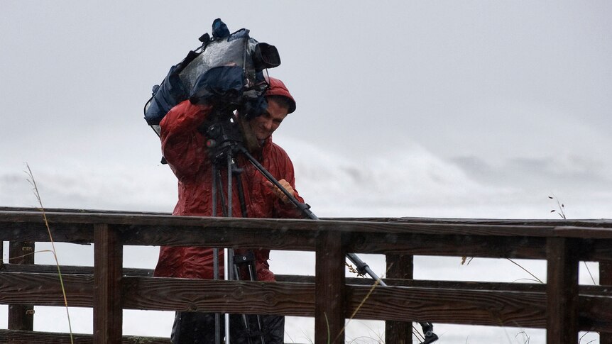A cameraman fights the wind and rain as Hurricane Irene comes ashore. (Reuters: Steve Nesius)