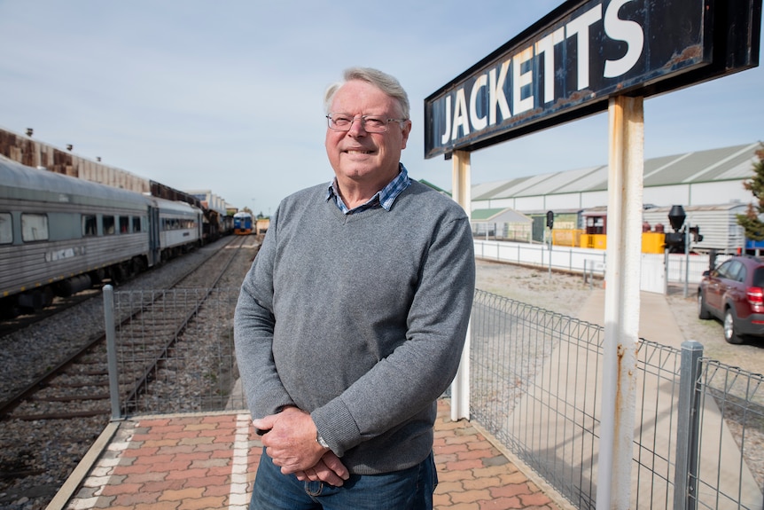 a man stands at a railway station entitled Jacketts