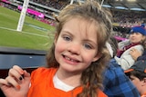Young girl smiling at football match in a large stadium