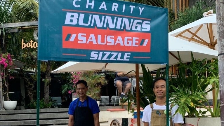 charity bunnings sausage sizzle sign with men standing underneath