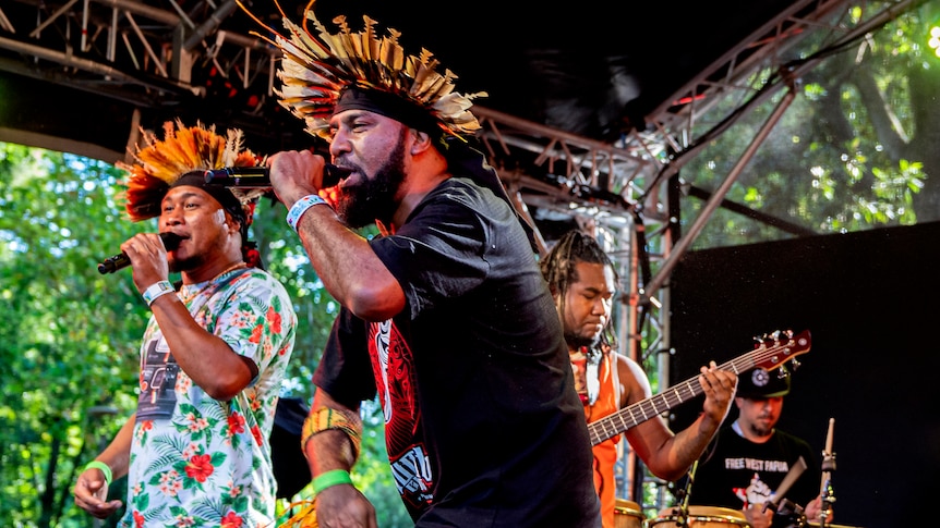 A group in tribal dress singing on stage.