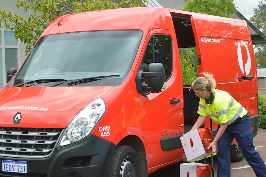 A woman unloading boxes out of an Australia Post van