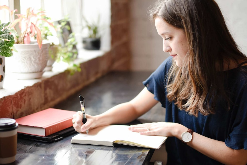 Woman writing in a cafe with a journal