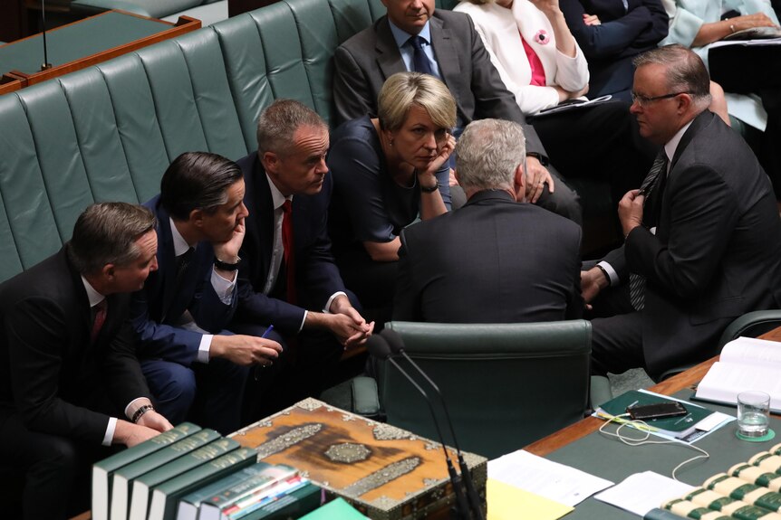 Labor politicians huddle in the House of Representatives. Tanya Plibersek is the only woman in the group