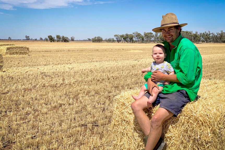 Farmer Cam Parker sitting on a hay bale with his toddler son Freddie.