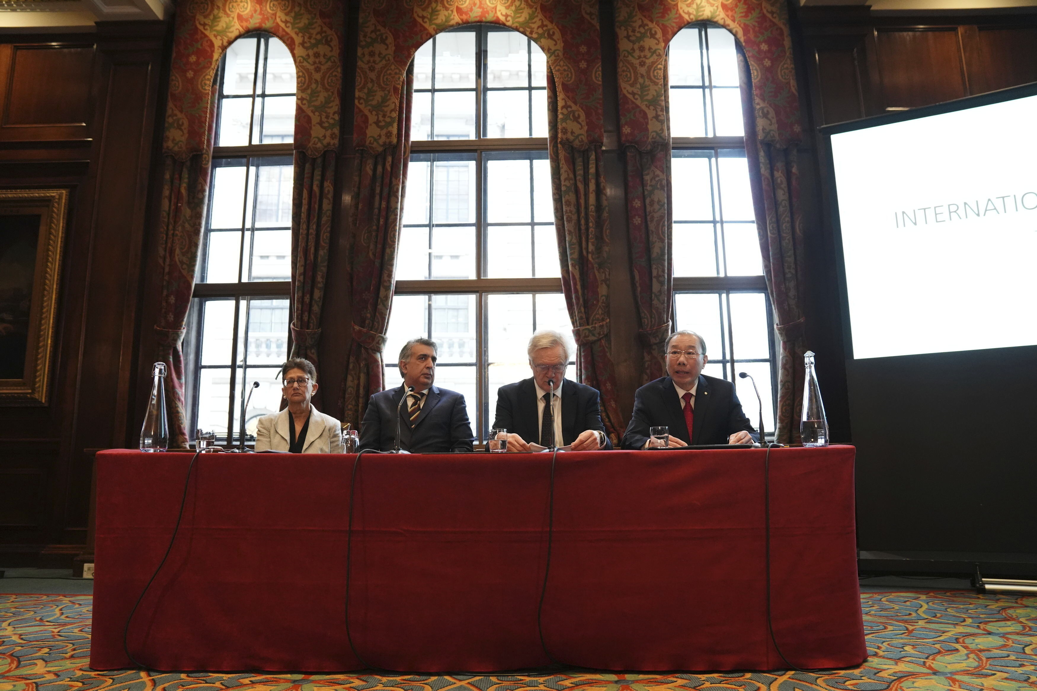 Four people sitting at an office in an old parliamentary room.