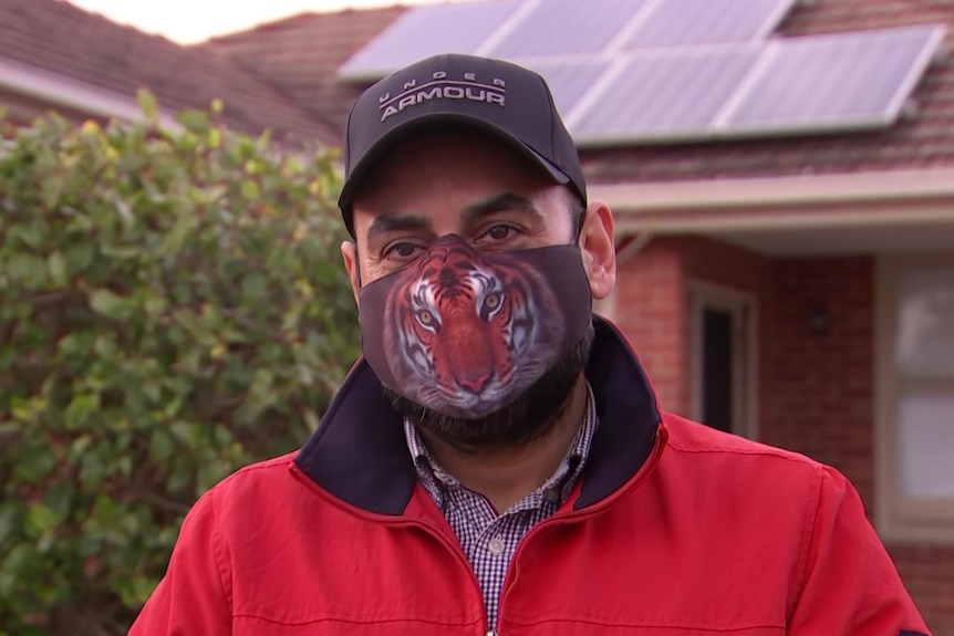 An Adelaide man stands outside a home with a face mask on.