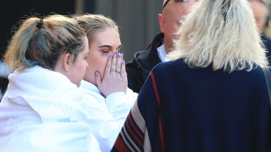 Two young girls, one crying, stand beside two adults.