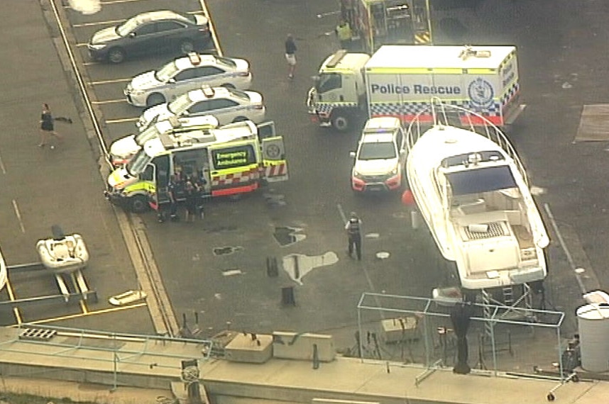 Police vehicles and ambulances at a marina.