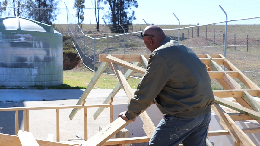 man building roof structure, facing away from camera.