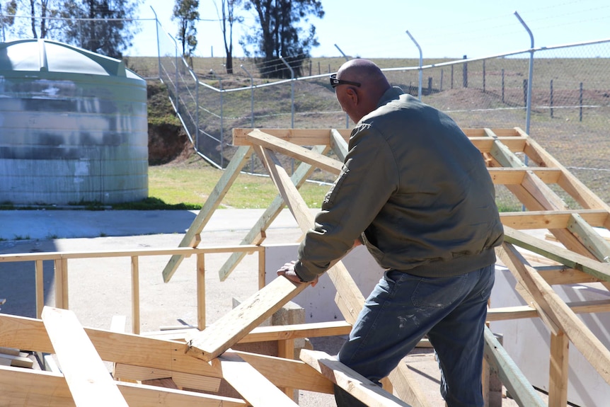 man building roof structure, facing away from camera.