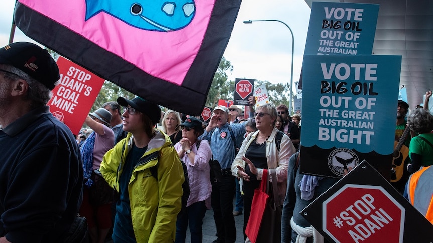 Protesters wave signs and placards urging action on several environmental issues.