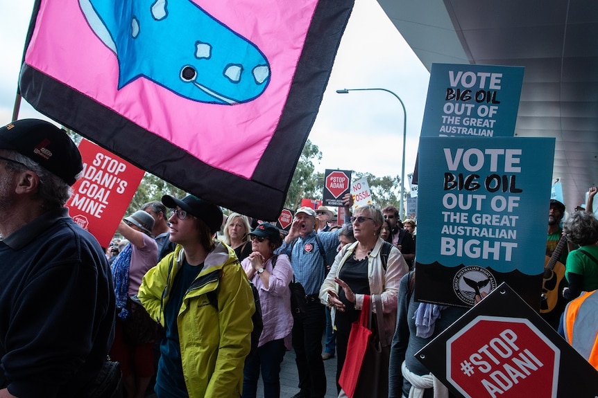 Protesters wave signs and placards urging action on several environmental issues.