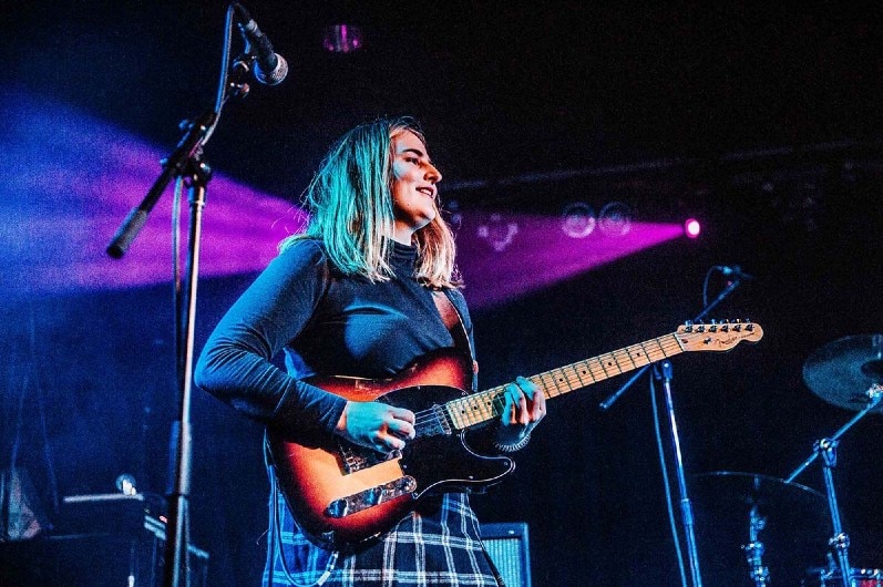 Woman plays guitar and sings on stage