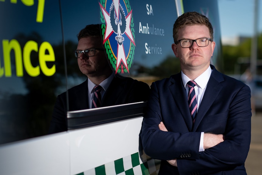 South Australian Health Minister Chris Picton stands next to an ambulance. 