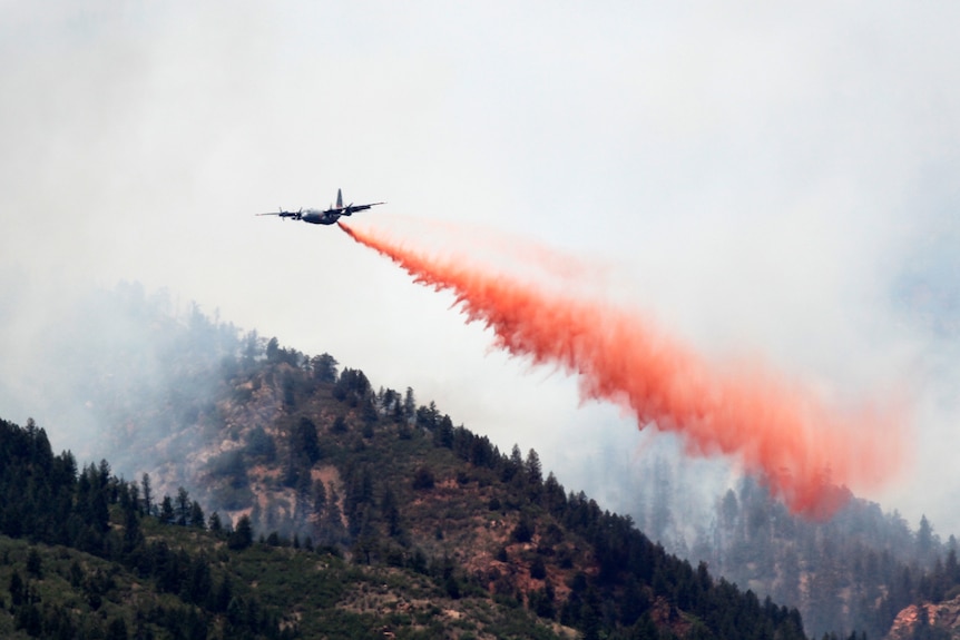 A C-130 military cargo plane drops thousands of gallons of retardant on the Waldo Canyon fire west.