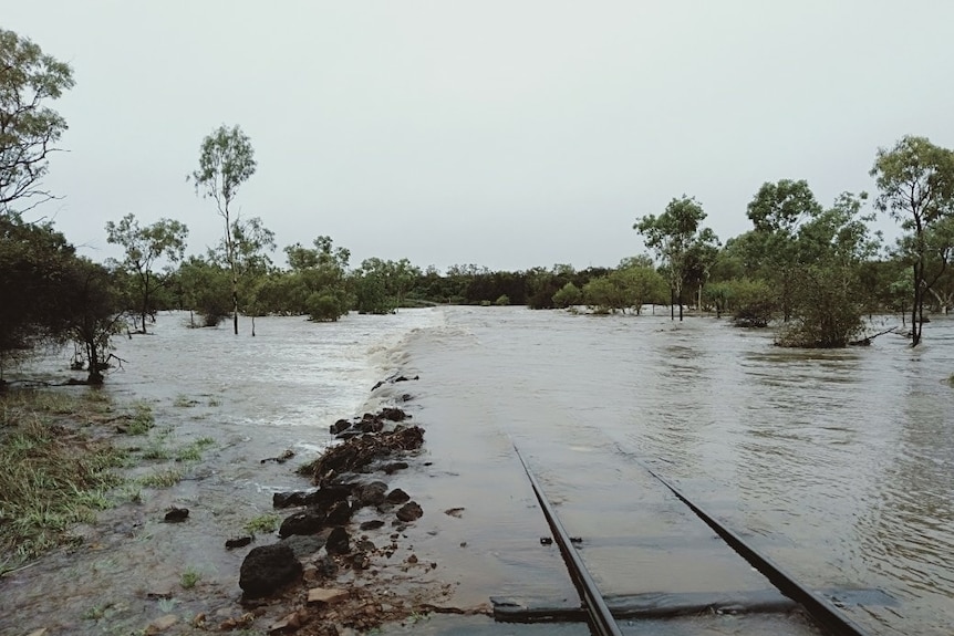 Water rushes over train tracks.