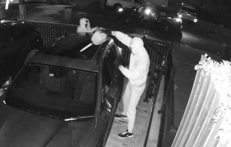 A person pouring petrol on a car in a black and white CCTV image