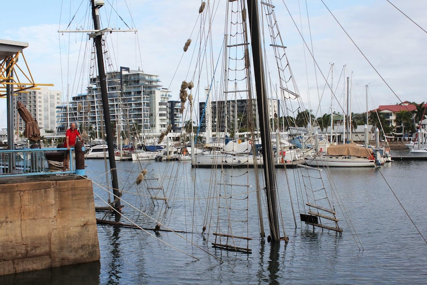 A man stands at a railing looking at sunken ship Defender in Ross Creek