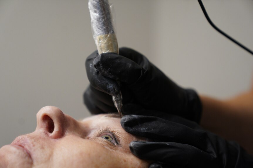A close up of a woman's eye and eyebrow as she is receiving a cosmetic tattoo