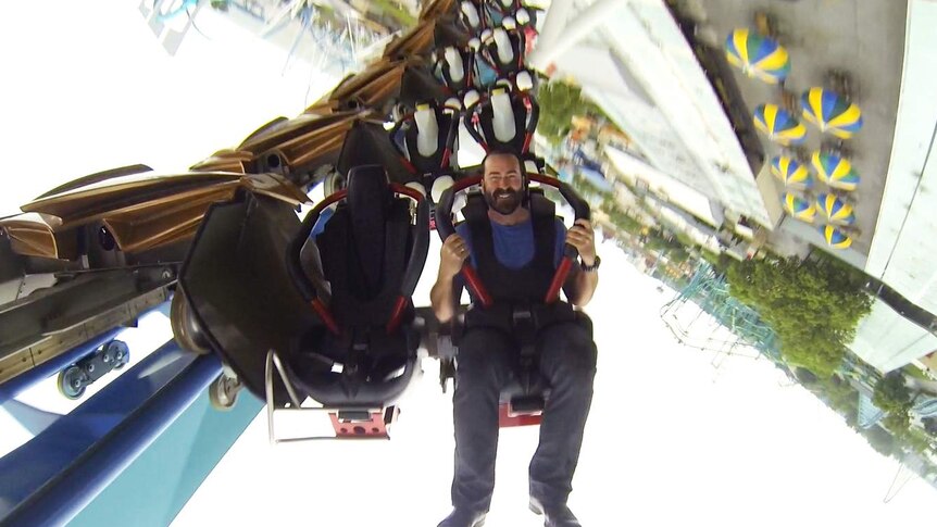 Image of Amusement academic Malcolm Burt riding upside down at the front of a rollercoaster