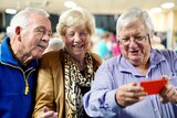 Jim Donaghy, Mavis Owens and Peter Francis standing looking at smartphone
