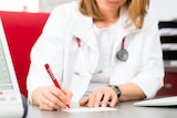 A female doctor wearing a stethoscope fills out a medical certificate