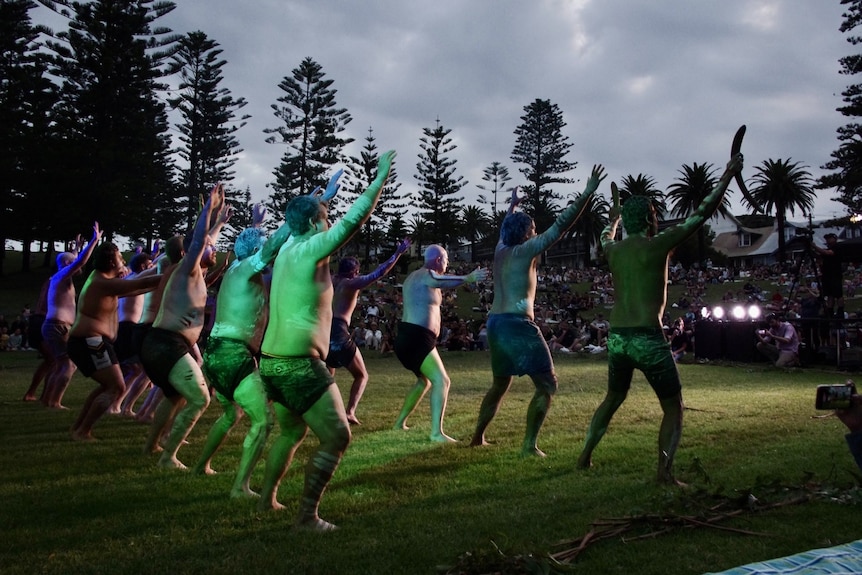 A group of Indigenous performers dancing in front of a crowd.