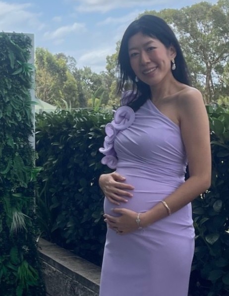 Tash Lay poses in a lilac formal gown cradling a visable baby bump.