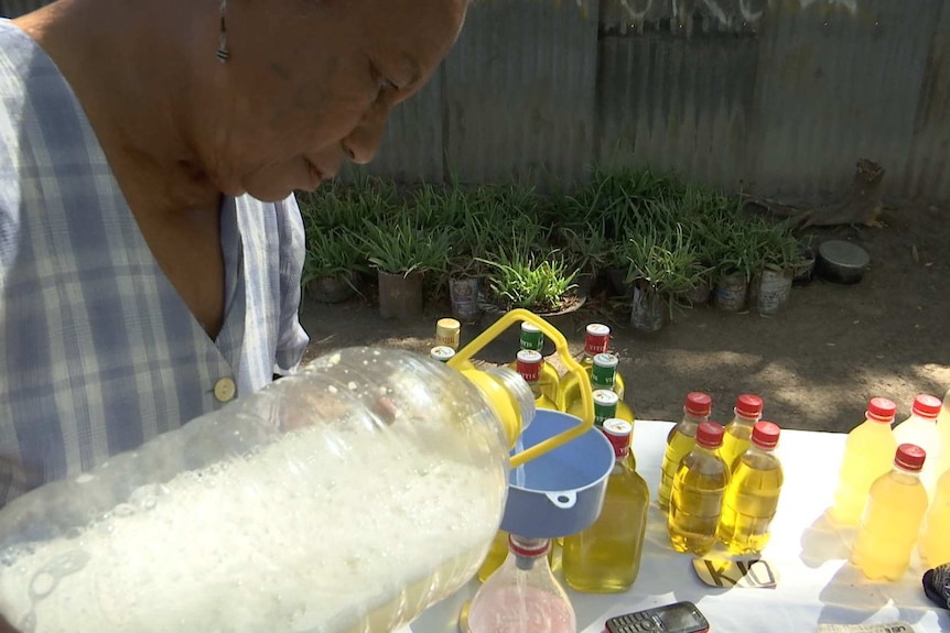 A woman pours yellow liquid into a bucket.