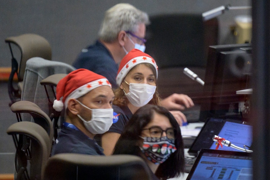 Launch teams wearing Santa hats monitor the countdown to rocket launch.