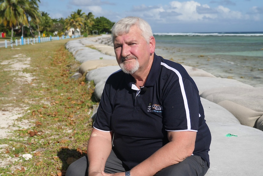 Shire of Cocos CEO Frank Mills sits at the top of the sea wall on West Island.