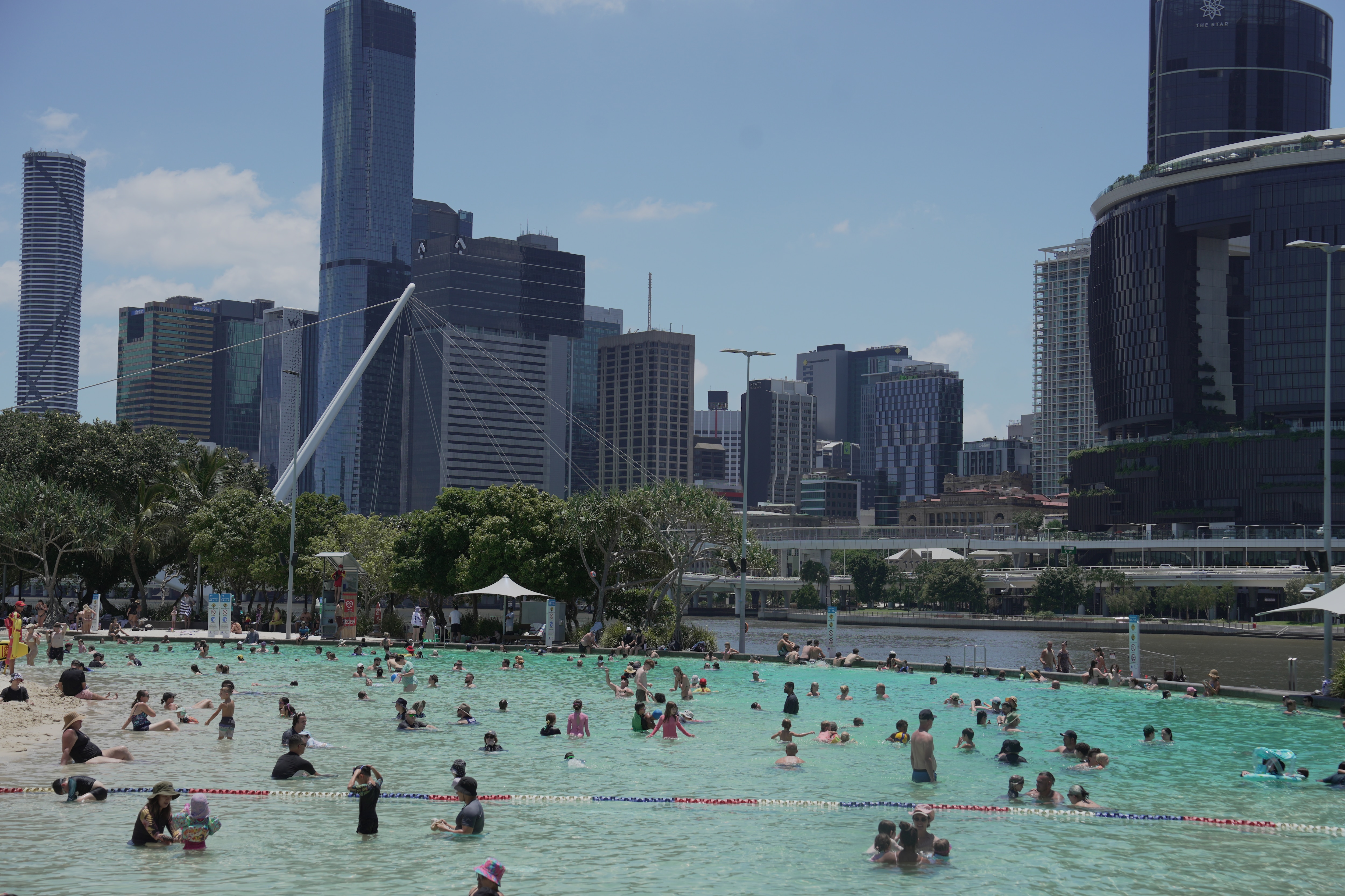 Una multitud de personas en una laguna con el horizonte de Brisbane al fondo.