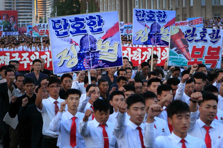 North Koreans hold anti-america signs with imagery of missiles hitting the US Capitol building.