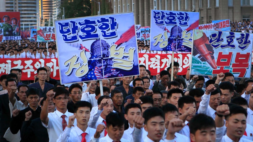 North Koreans hold anti-america signs with imagery of missiles hitting the US Capitol building.