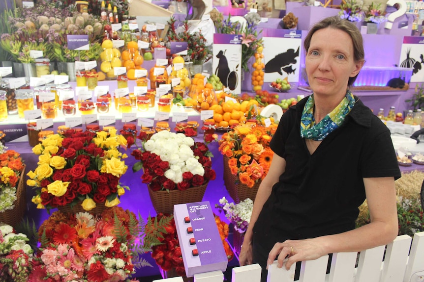 A woman stands in front of a floral display.