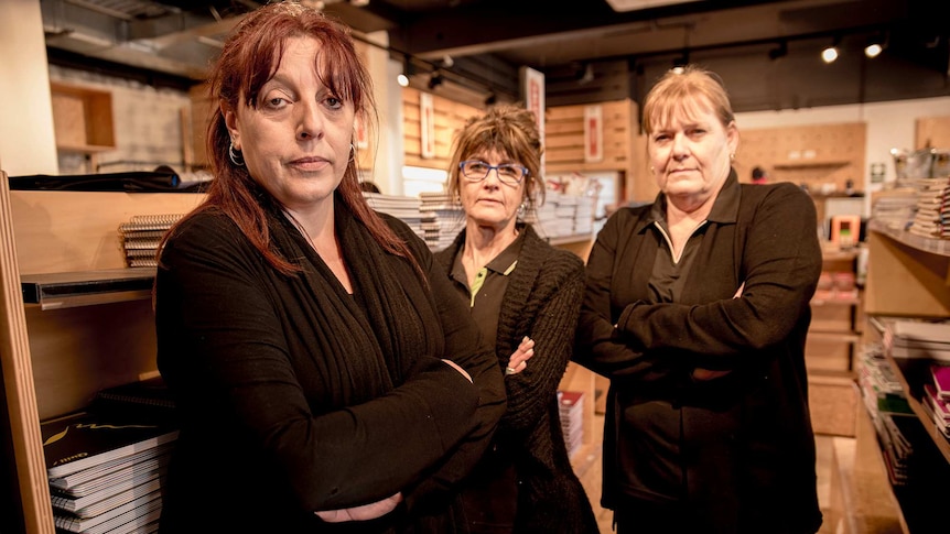 Three women stand inside a retailer looking very annoyed.