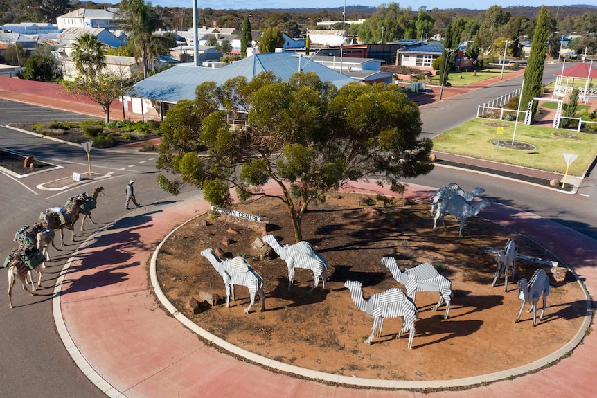 An aerial shot of a camel train passing through the main street of Norseman in Western Australia.