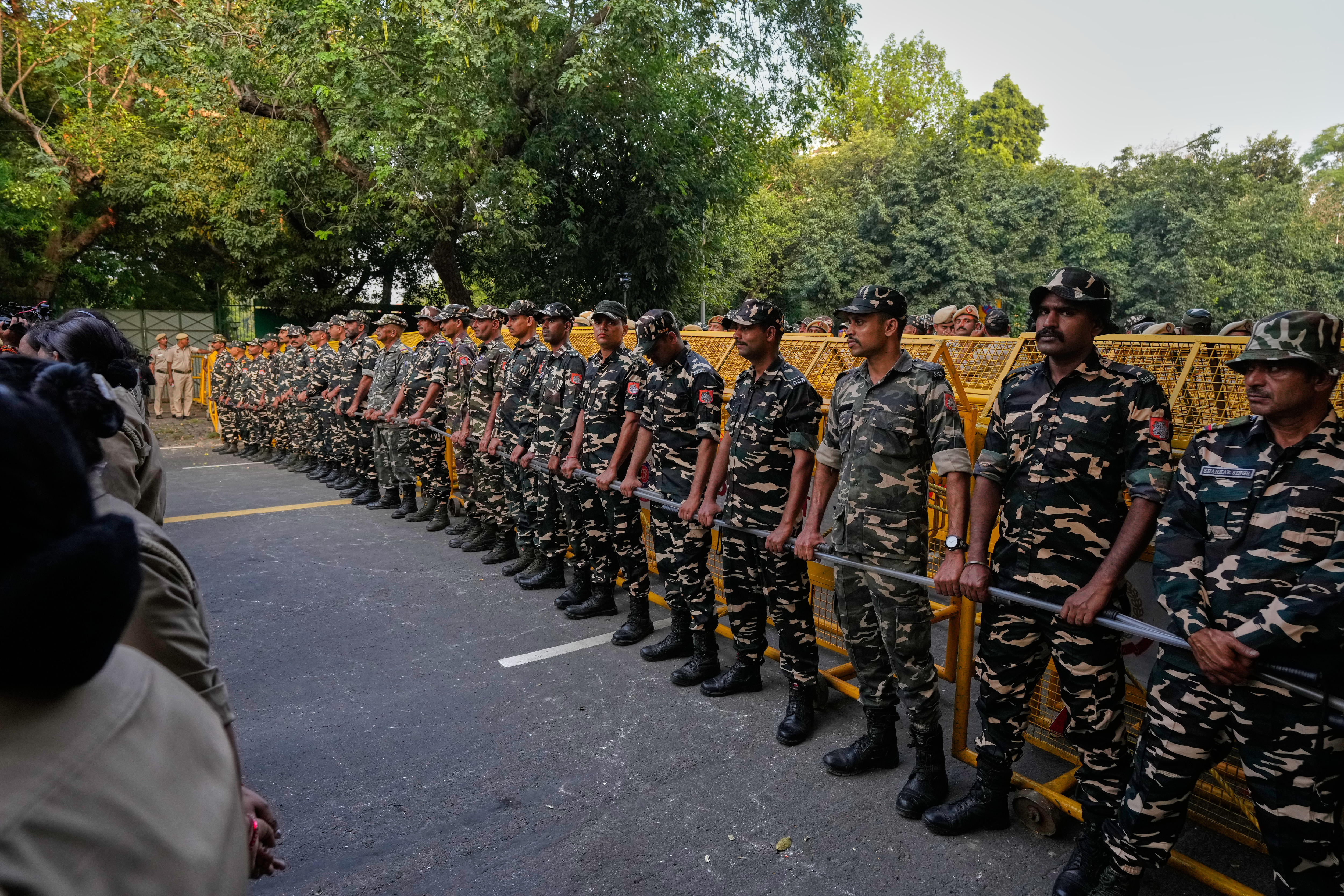 More than a dozen people in camoflague uniforms stand side by side across a road.