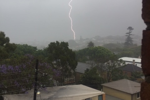 Lightning strikes an unseen target as skies in Sydney are an ominous grey during unprecedented storms.