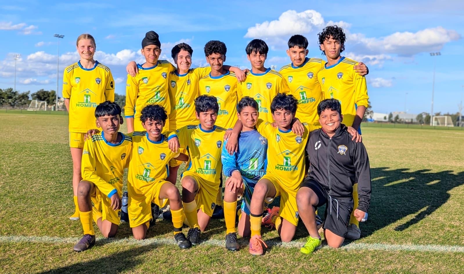 Thirteen soccer players posing for a photo at a soccer ground