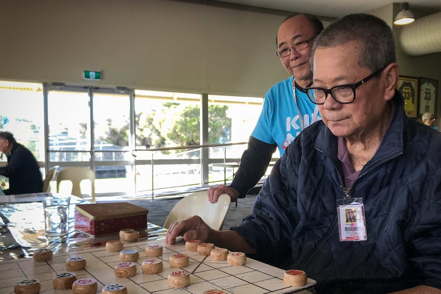 Volunteer Phillip Ong watches on during a Chinese chess game.