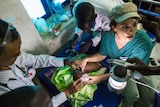 Nurse Jessica Hazelwood and other medical personnel use LED lights as they respond to baby Nyanene's breathing problems.