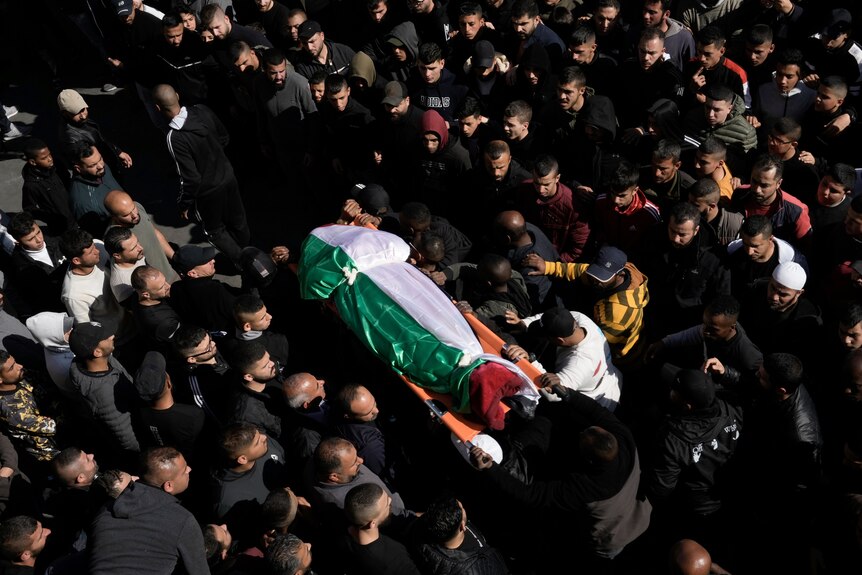 哀悼者在葬礼上抬着一具巴勒斯坦人的遗体。