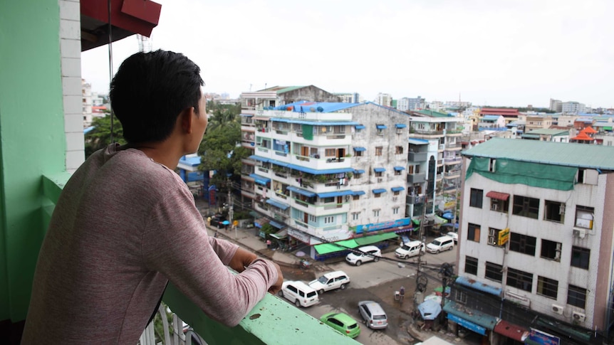 A young man gazes out of a balcony in Myanmar