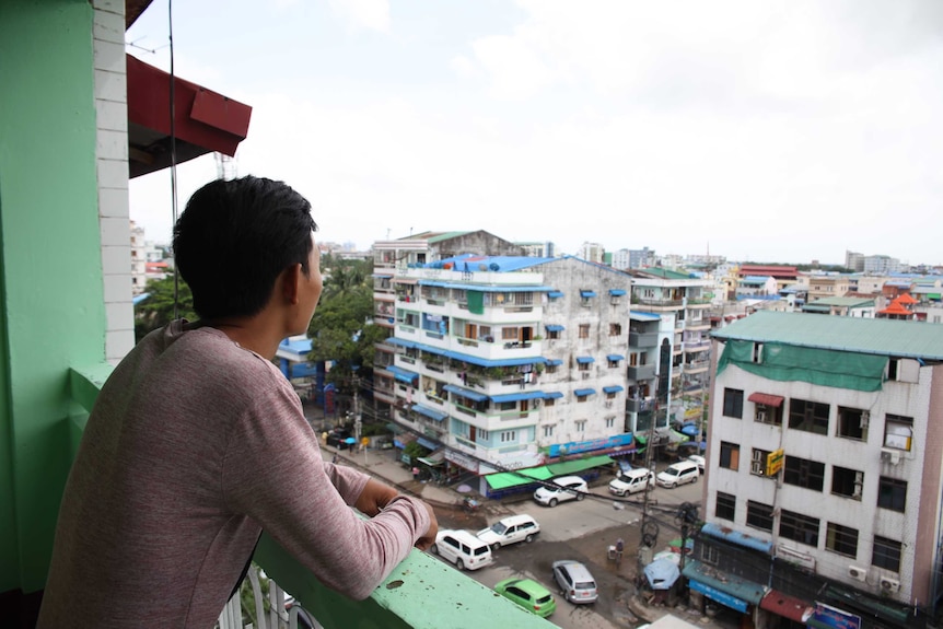 A young man gazes out of a balcony in Myanmar