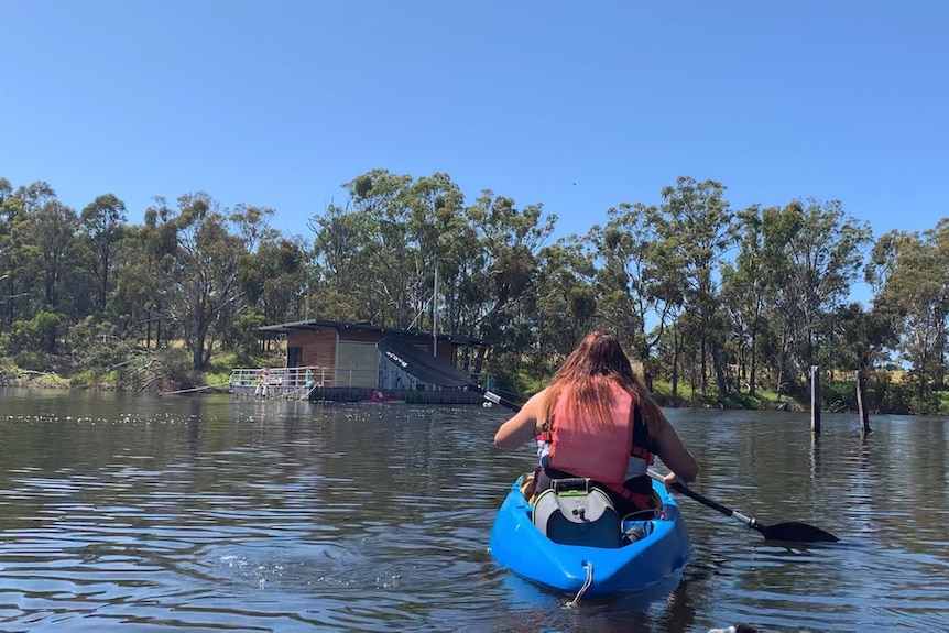 Alice on kayak travelling towards floating art gallery