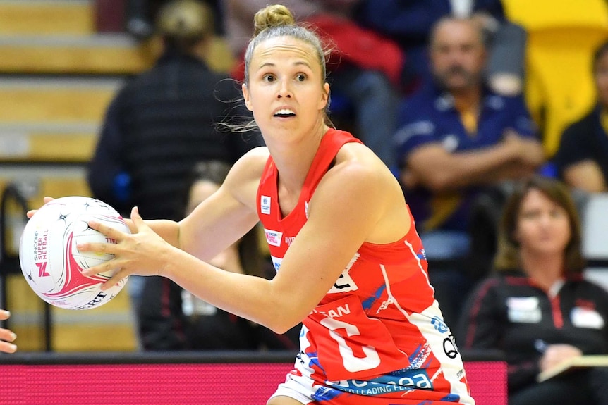 A NSW Swifts Super Netball player holds the ball in both hands as she prepares to pass against Adelaide Thunderbirds.